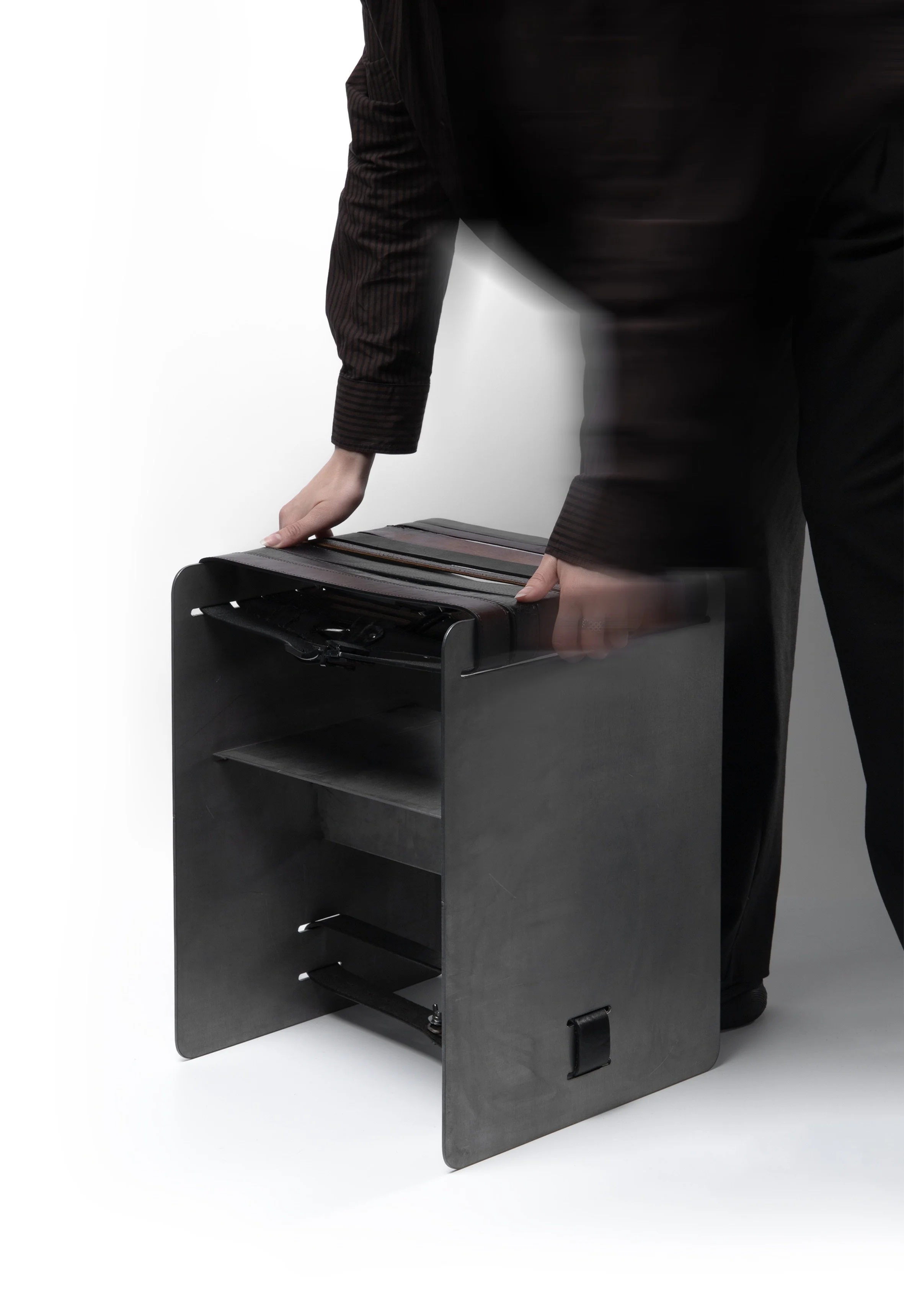 Person adjusting a black desk or machine with a glass top, against a white background.