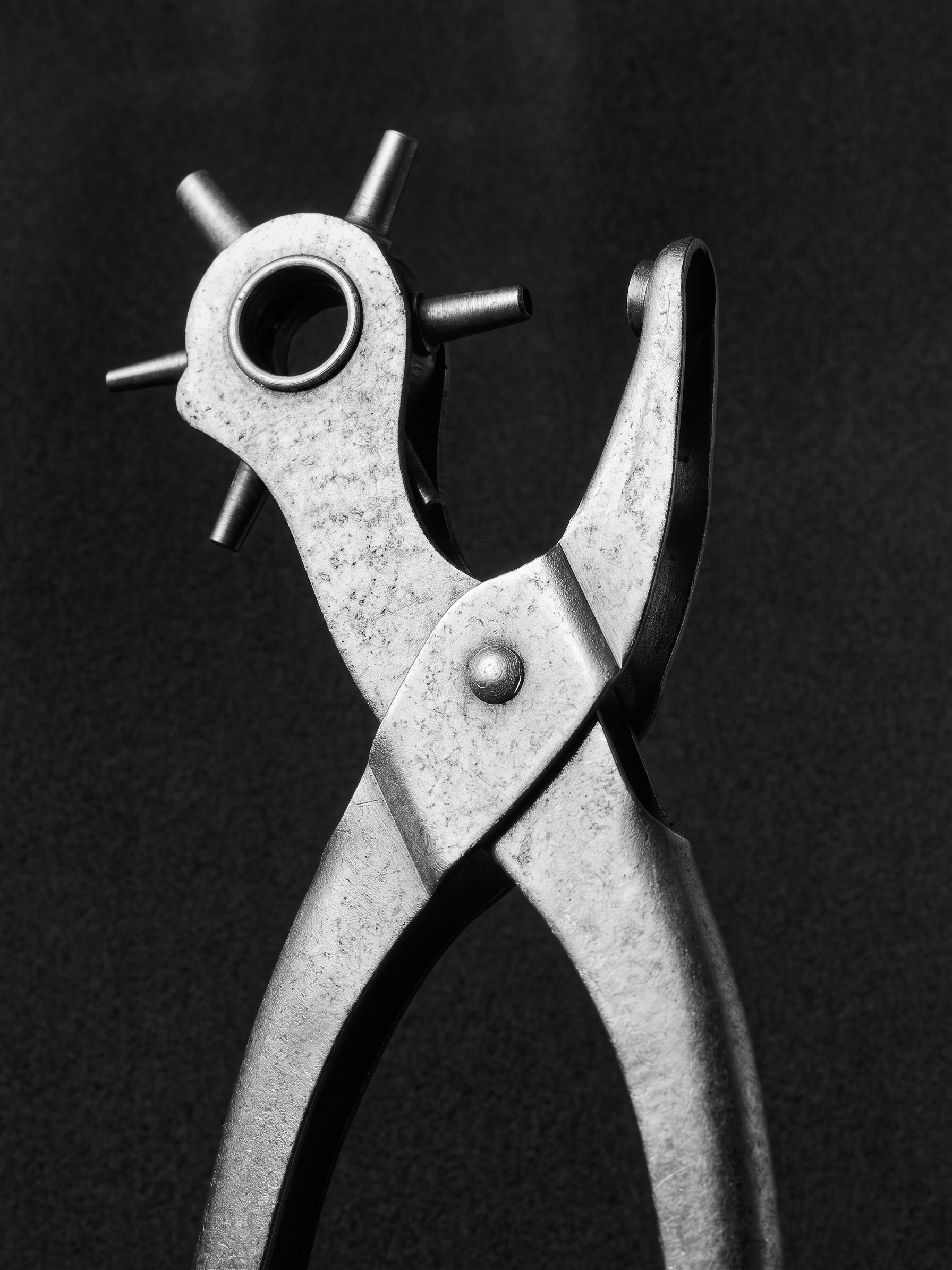 Black and white photograph of a pair of pliers and a metal bracket against a dark background.  Architecture and Design by Auliseo (Aurèle Eliseo Stauffer).