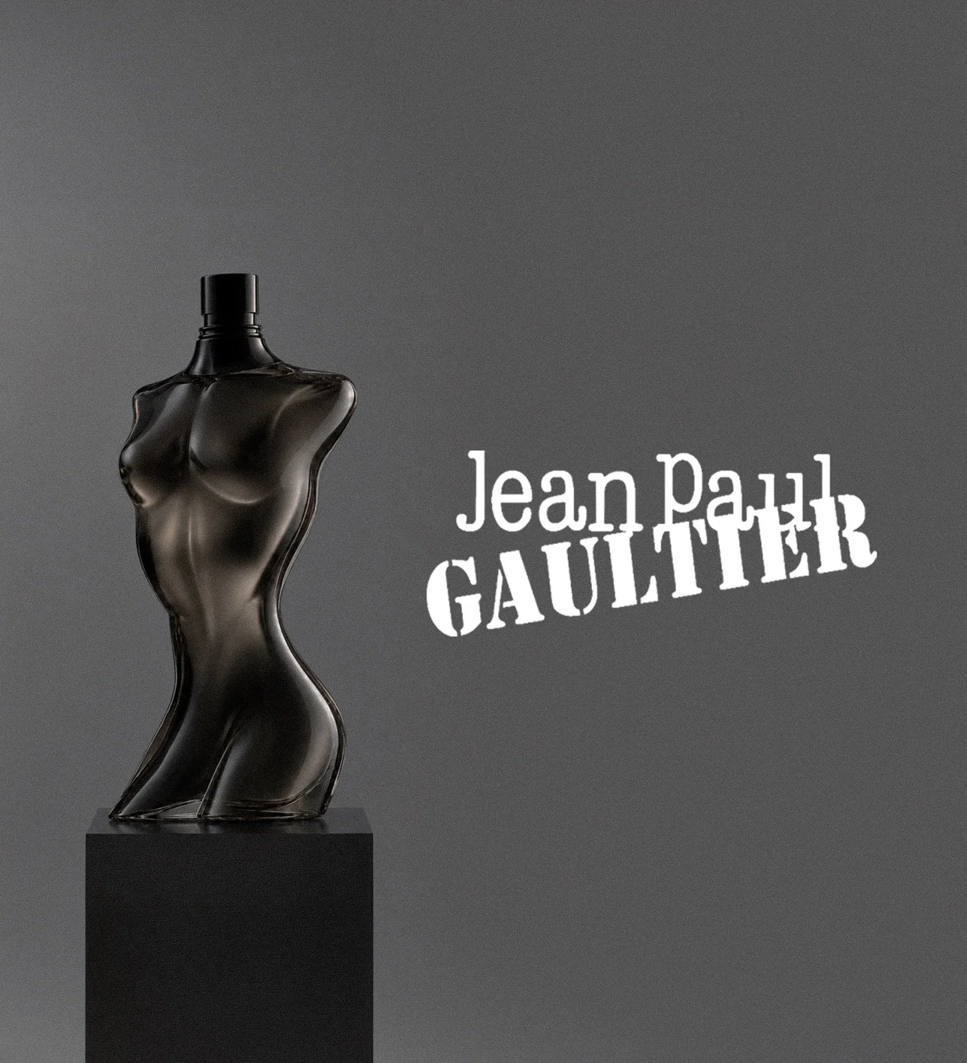 A black glass perfume bottle of a female and male torso on a black pedestal against a gray background, with the text 'Jean Paul Gaultier' in white to the right. Architecture and Design by Auliseo (Aurèle Eliseo Stauffer).