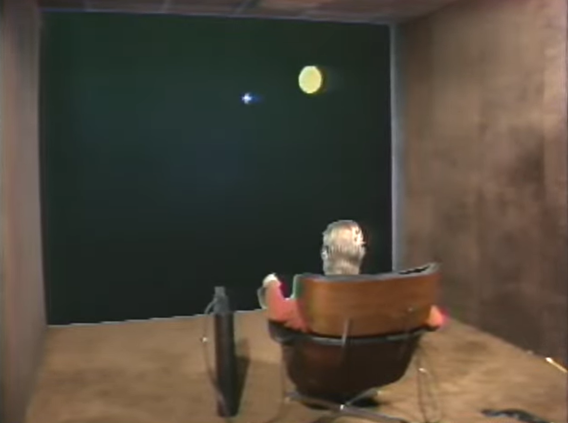 Put-That-There demonstration: a seated person in an Eames Lounge Chair faces a wall-sized screen.