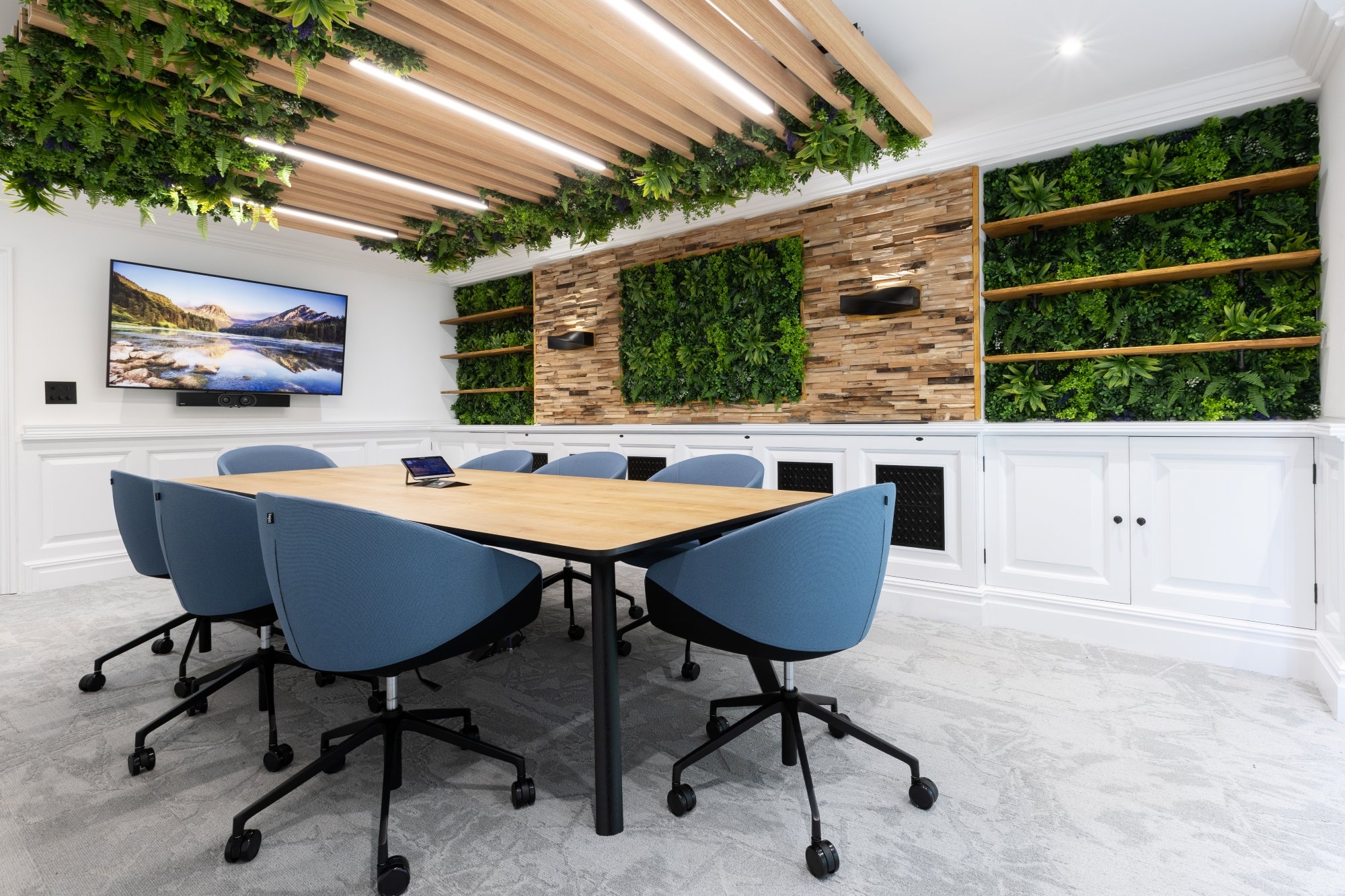 Healthspan meeting room with a timber table, blue chairs, planted wall panels and acoustic ceiling beams