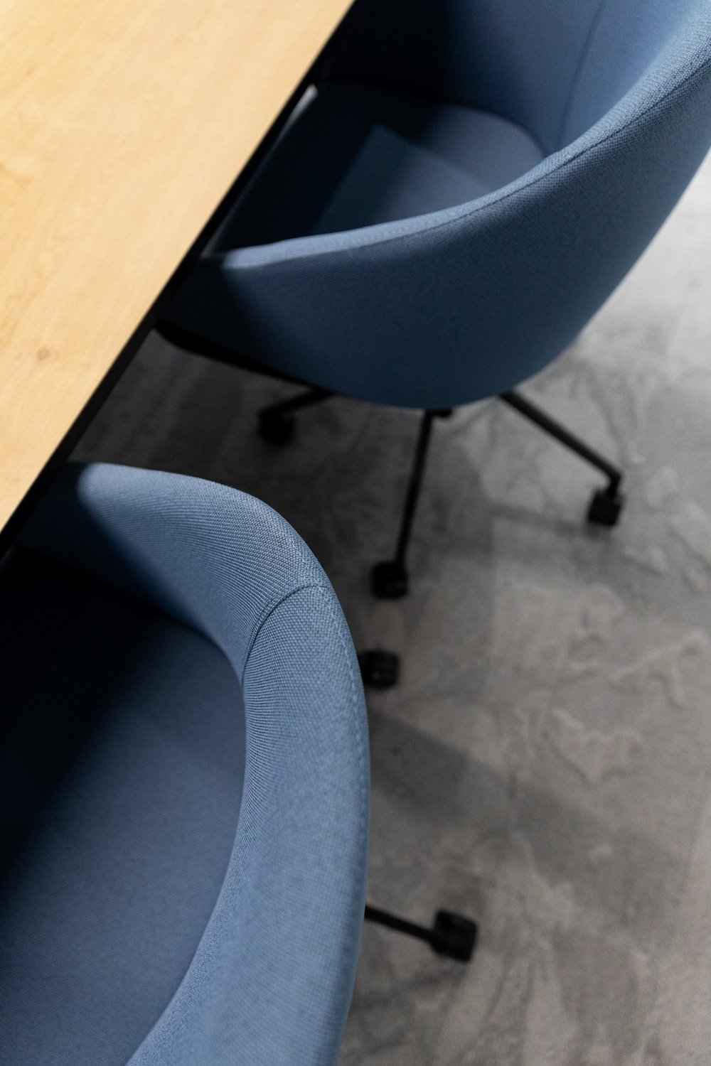 Detail of blue meeting chairs beside the timber table