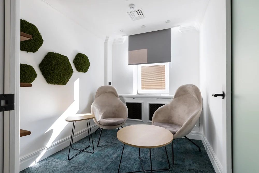 Healthspan one-to-one room with two high-back armchairs, a small table and green wall panels