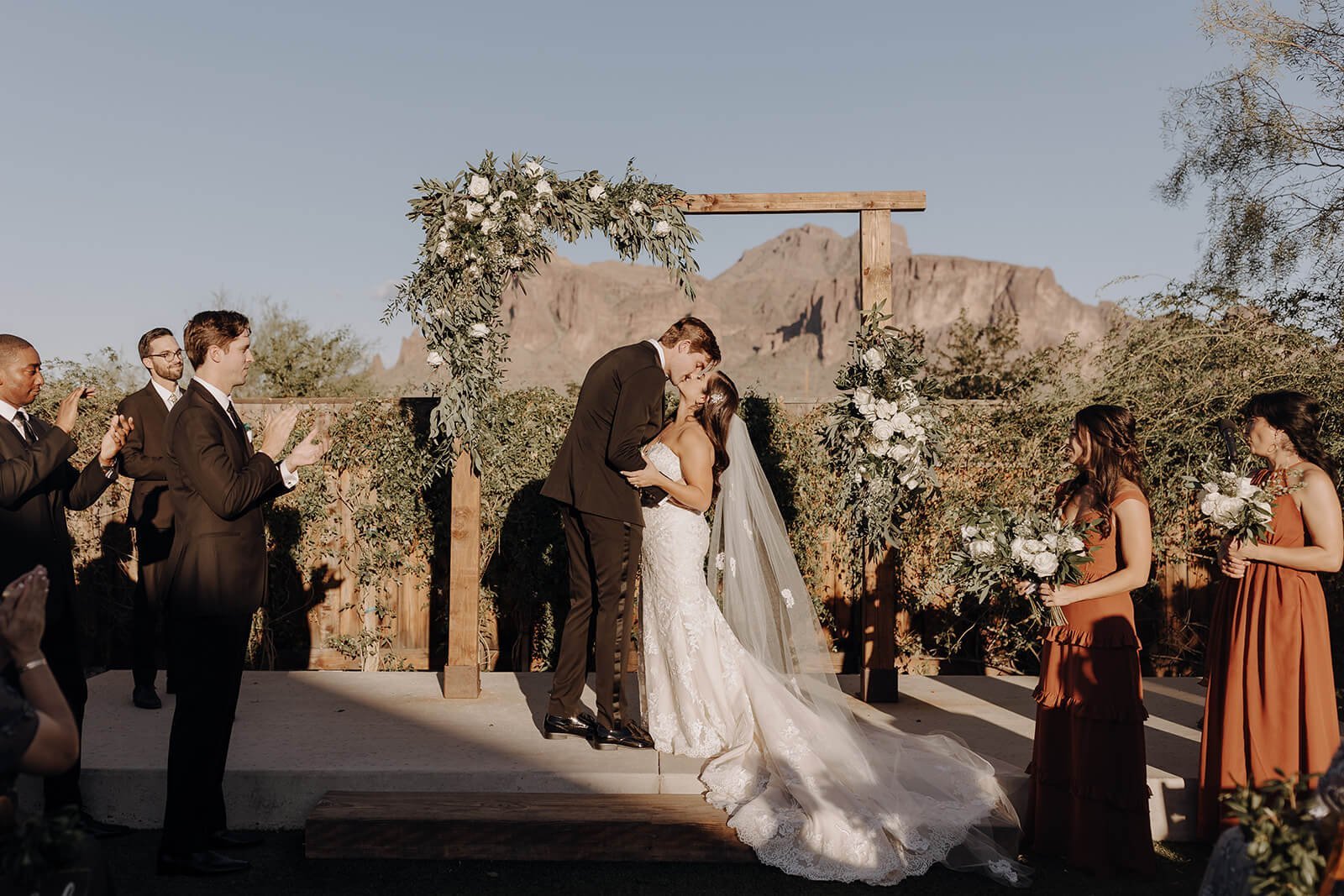 Bride and groom kissing in outdoor Arizona destination wedding with mountains in the background