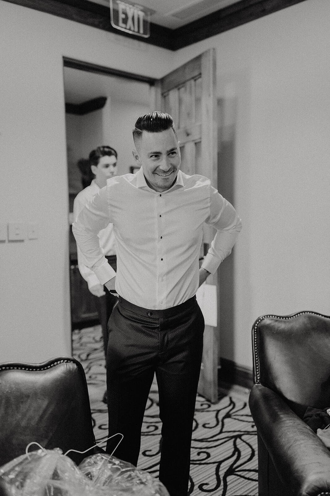 Black and white photo of groom getting ready for wedding