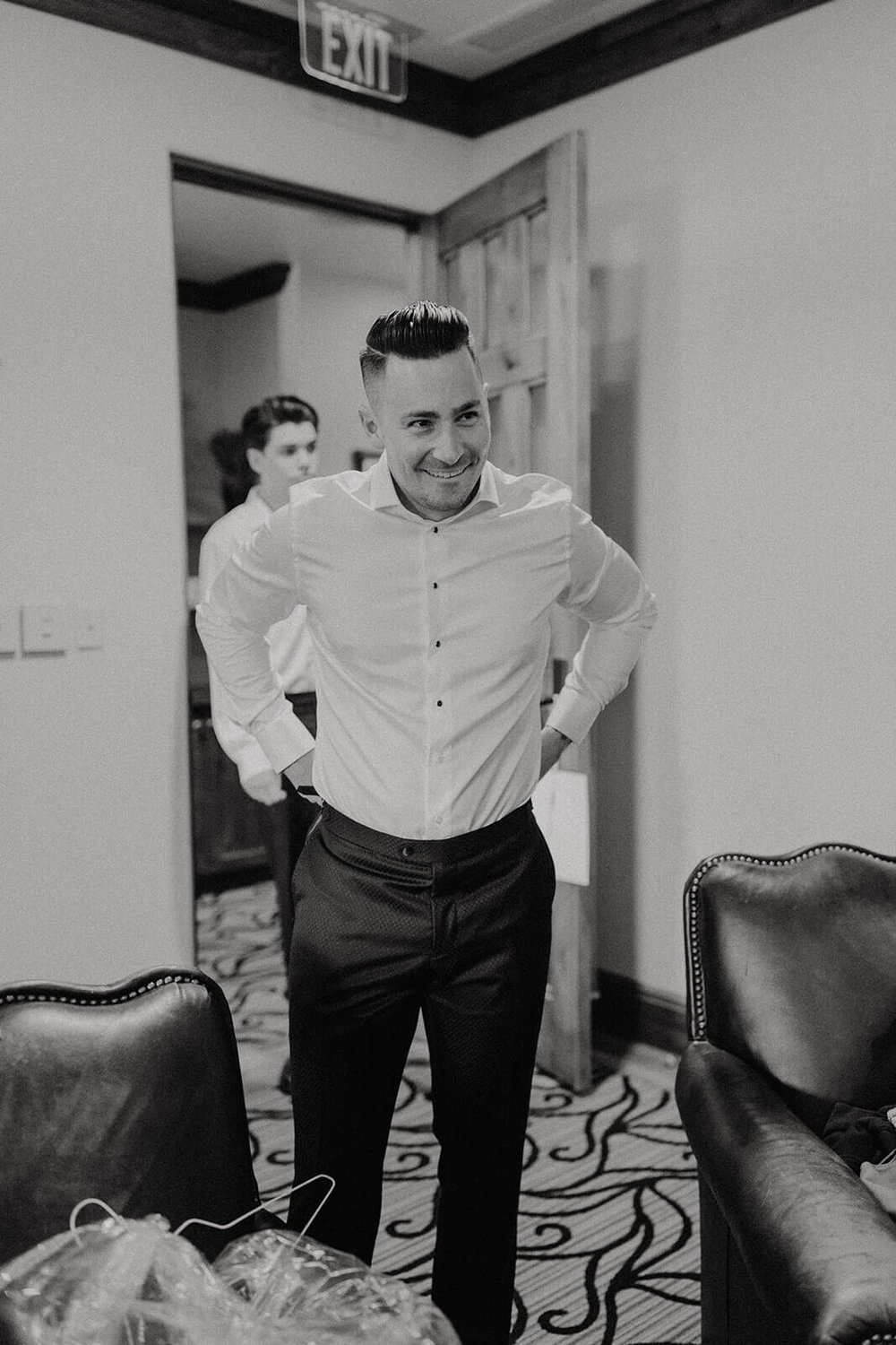 Black and white photo of groom getting ready for wedding