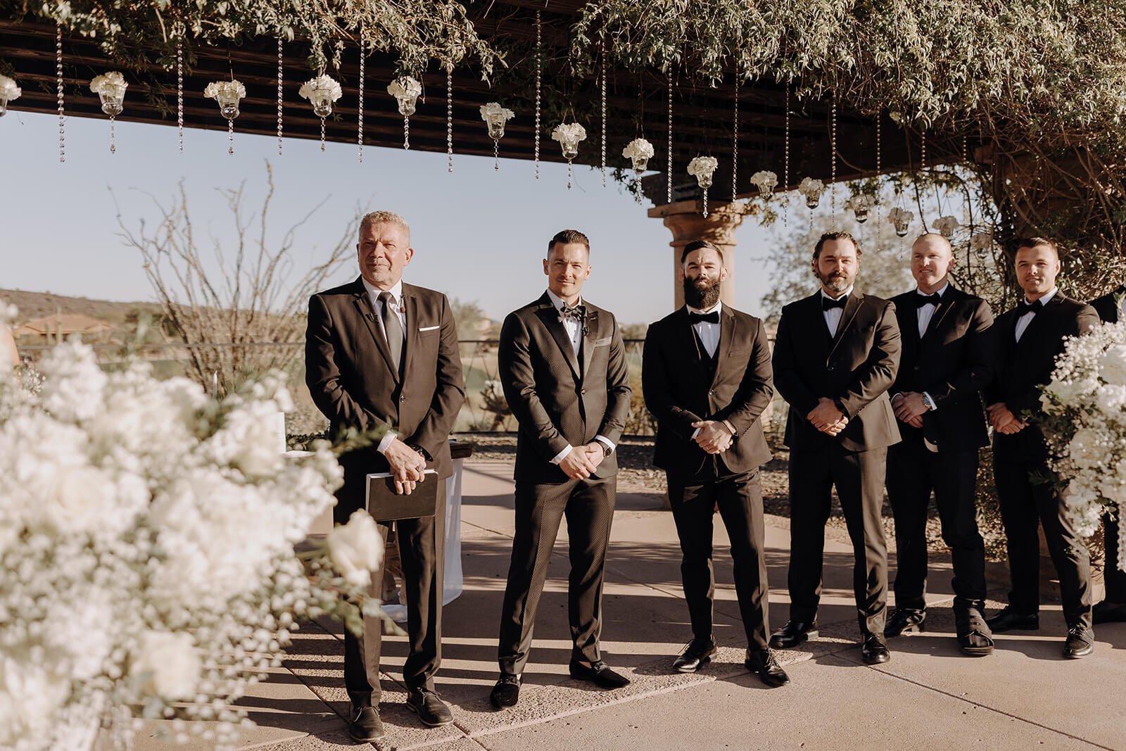 Groom and groomsmen standing under arbor at Blackstone Country Club in Arizona
