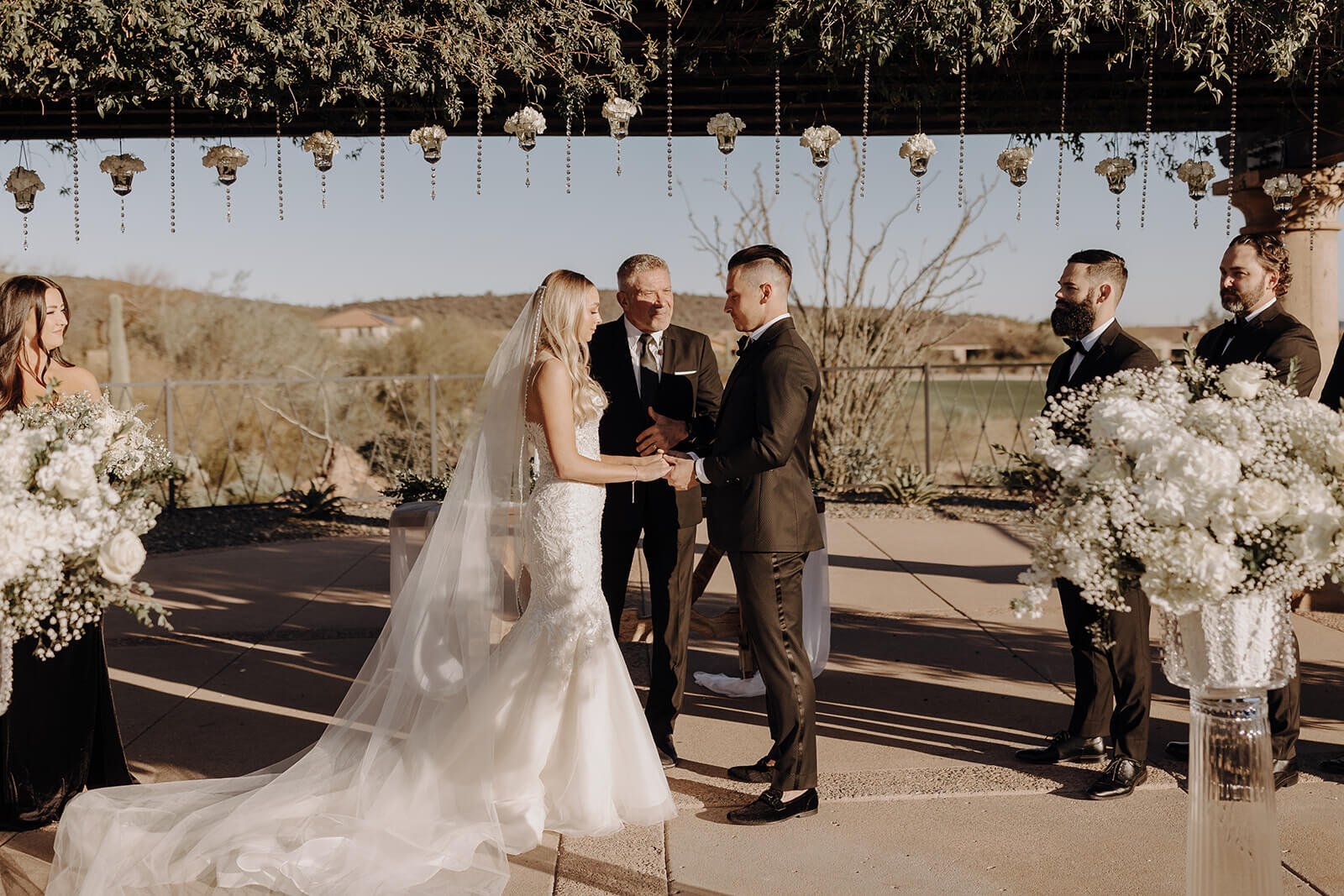 Bride and groom standing under a beautiful sunny arbor at an outdoor ceremony in Arizona