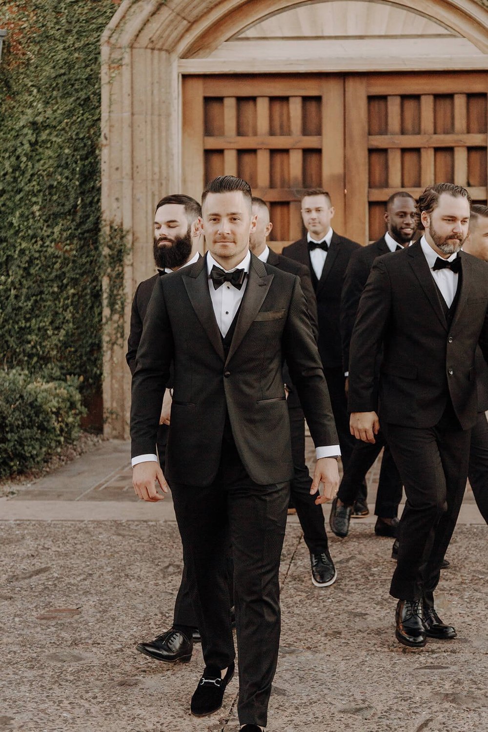 Groom walking with groomsmen at classy black and white Arizona wedding