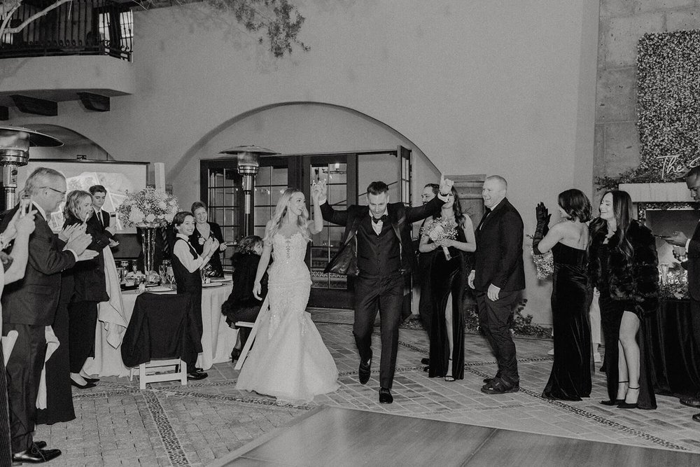 Black and white photo of bride and groom entering wedding reception at Blackstone Country Club