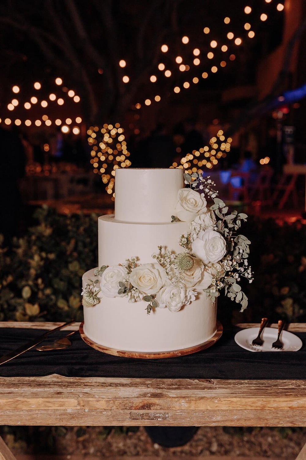 Beautiful three-tiered wedding cake with floral decorations at classy black and white wedding