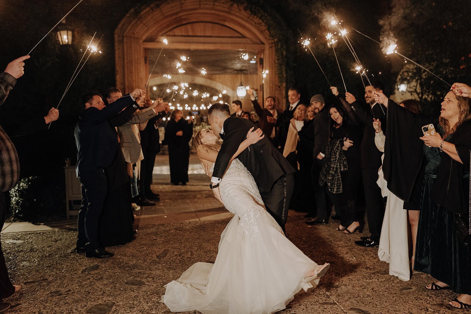 Groom dipping bride at end of sparkler sendoff at classy black and white Arizona wedding