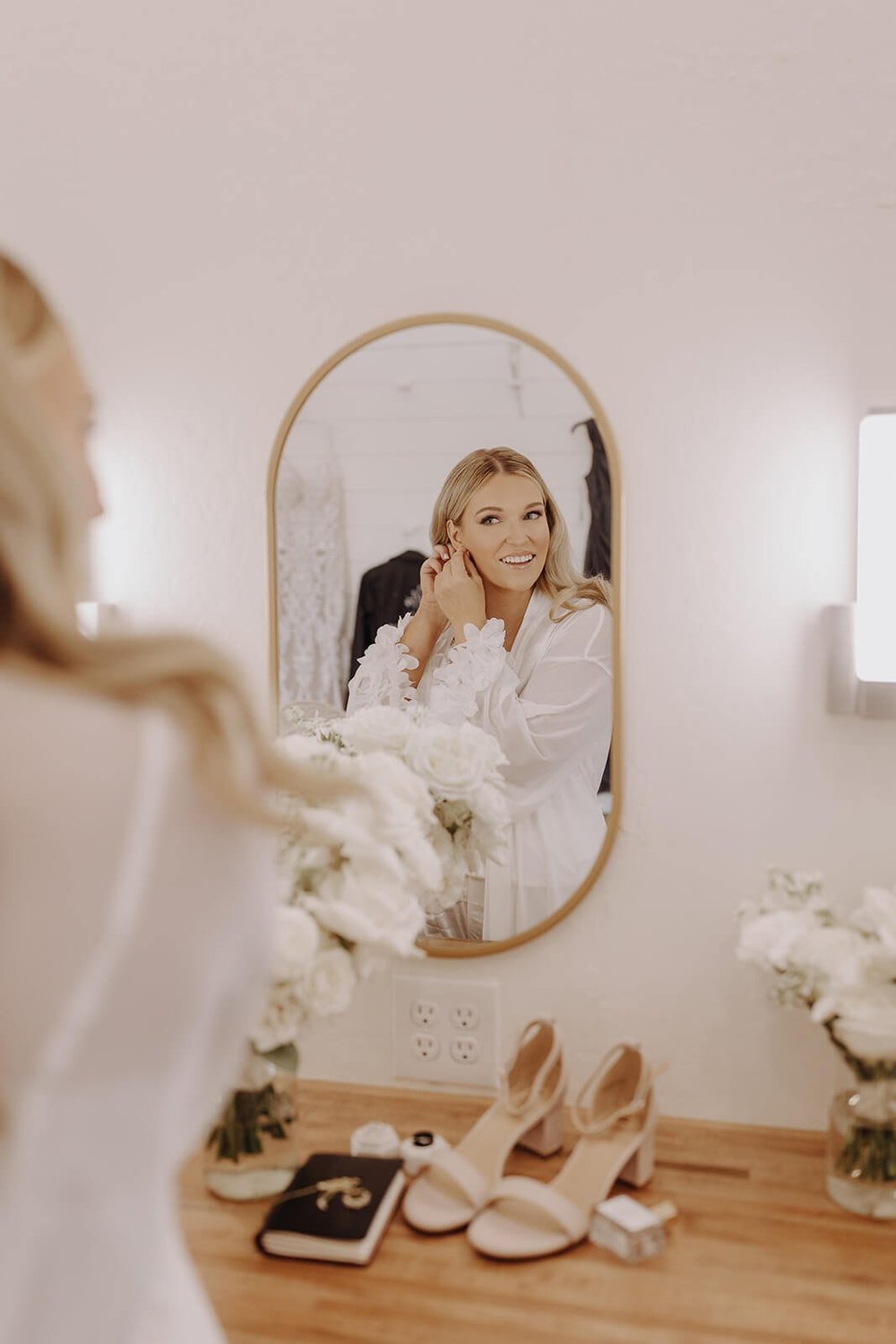 Bride wearing silk robe getting ready in mirror 