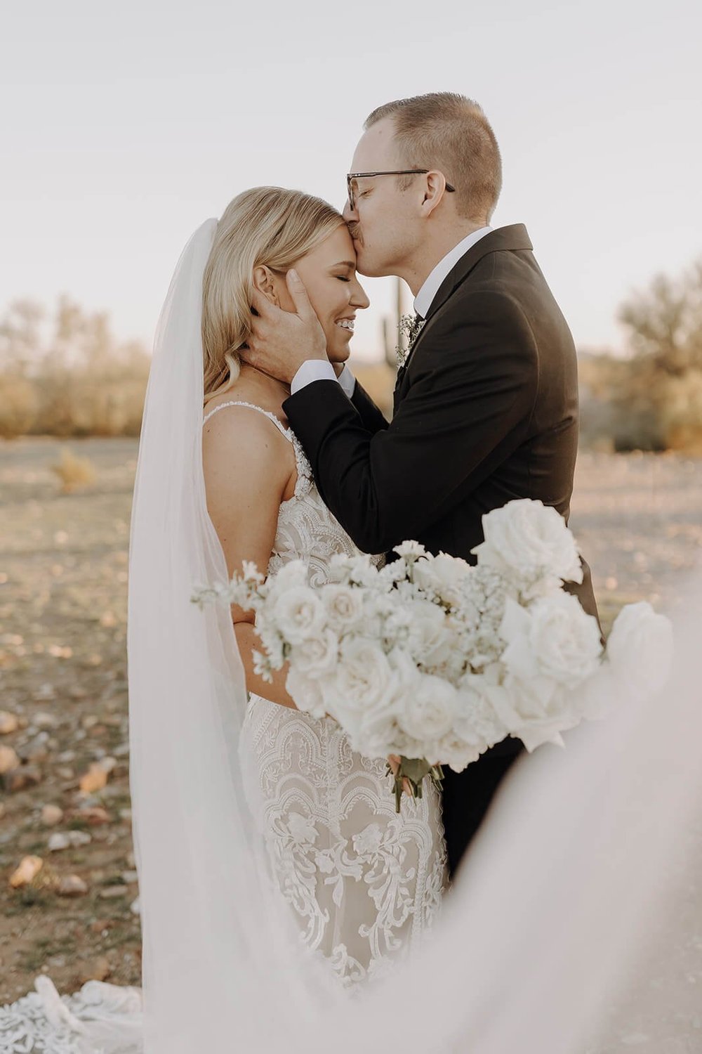 Groom kissing bride's forehead outside at Arizona destination wedding