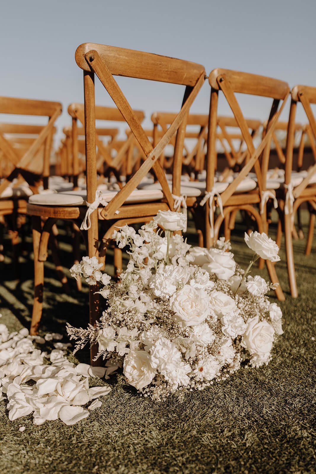 Close up of wooden ceremony guest chairs and white floral bouquet outside at Arizona destination wedding