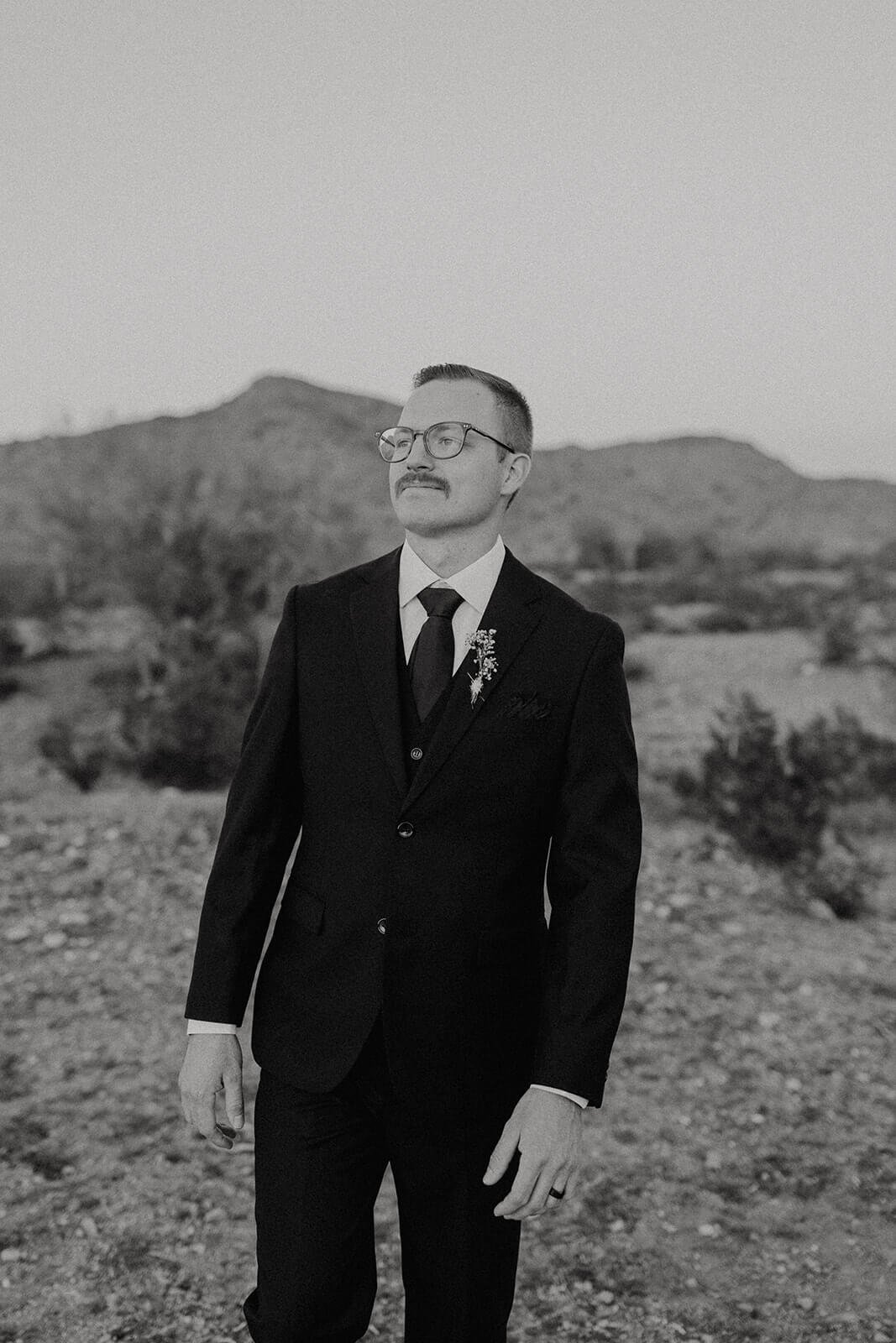 Black and white photo of groom in the desert