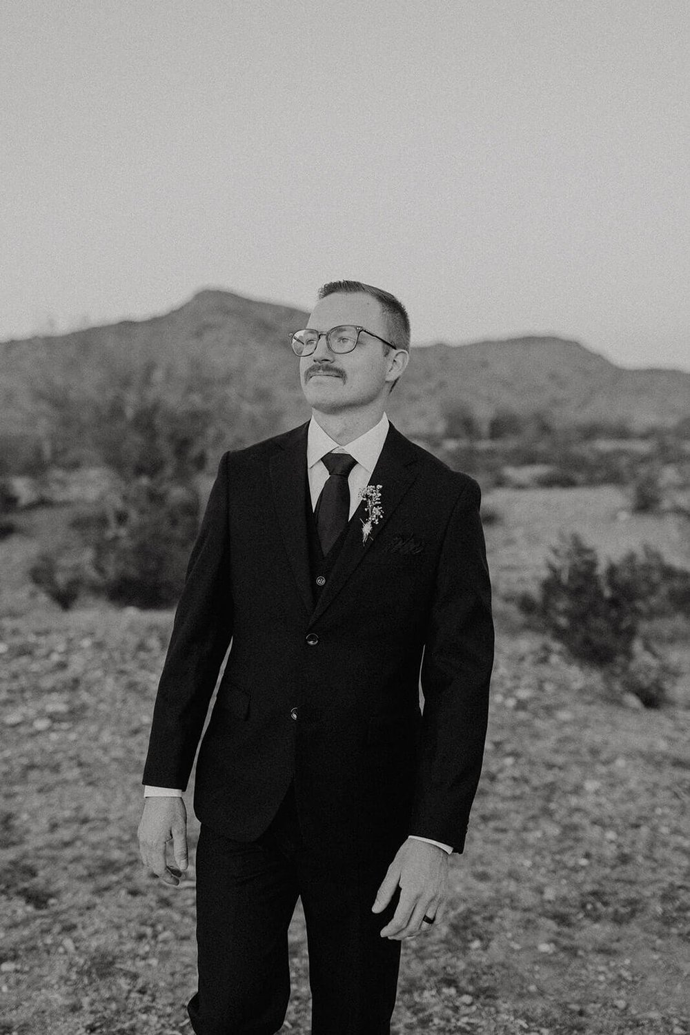 Black and white photo of groom in the desert