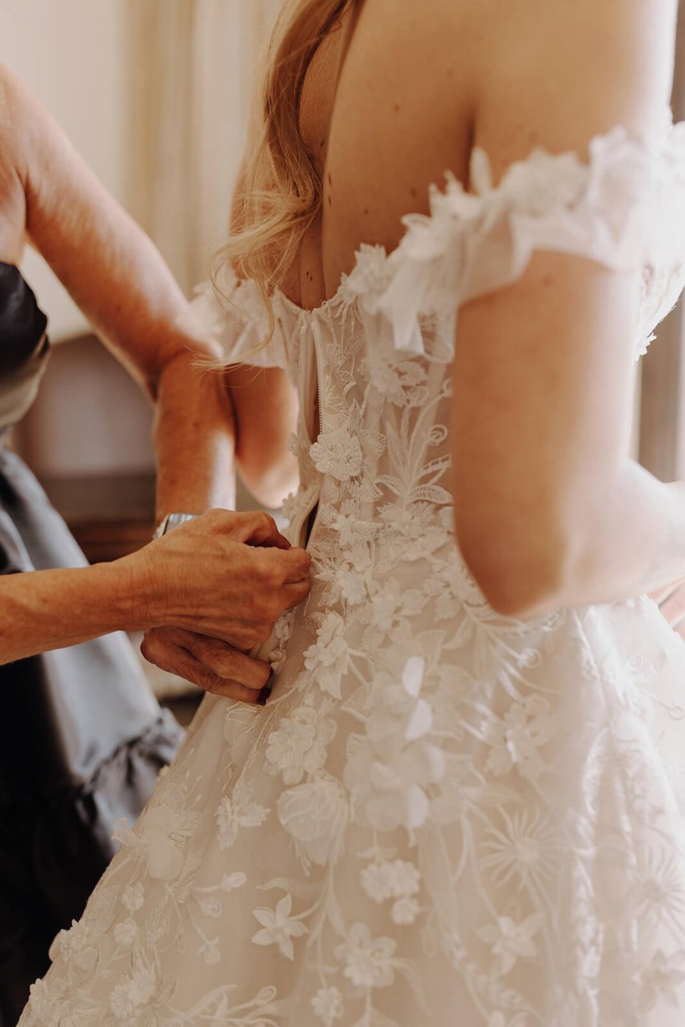 Backview of bride getting dressed in wedding gown