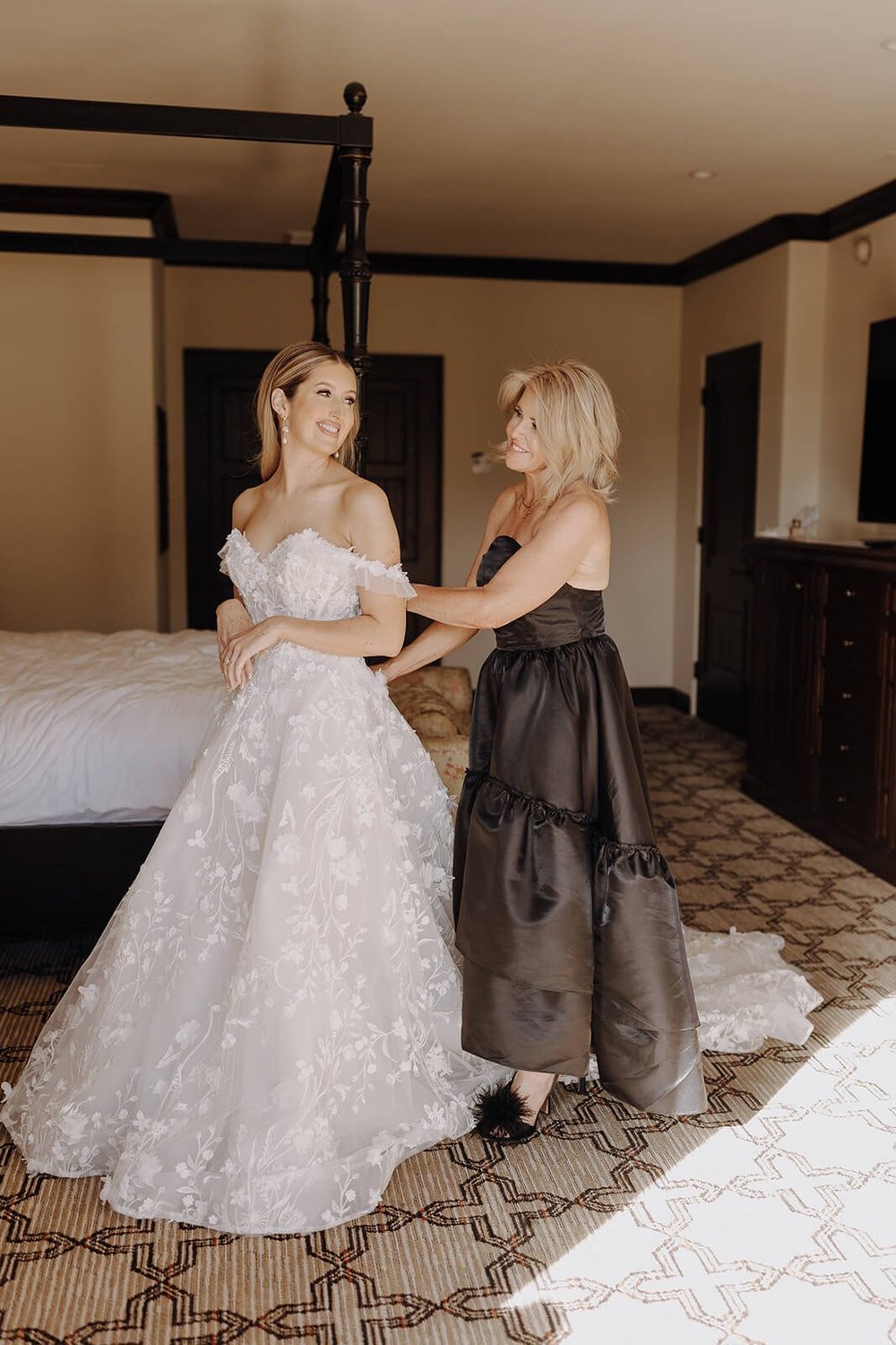 Mother of the bride helping bride get dressed for luxury wedding