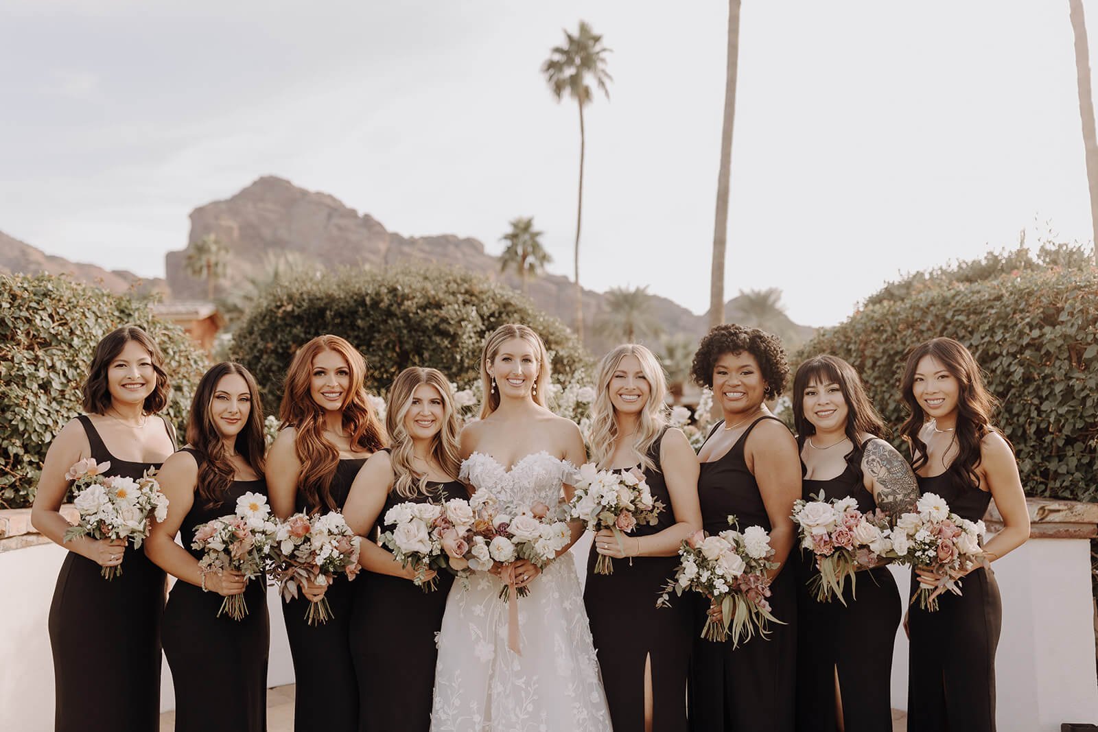 Bride and bridesmaids with floral boquets outside with mountains in background