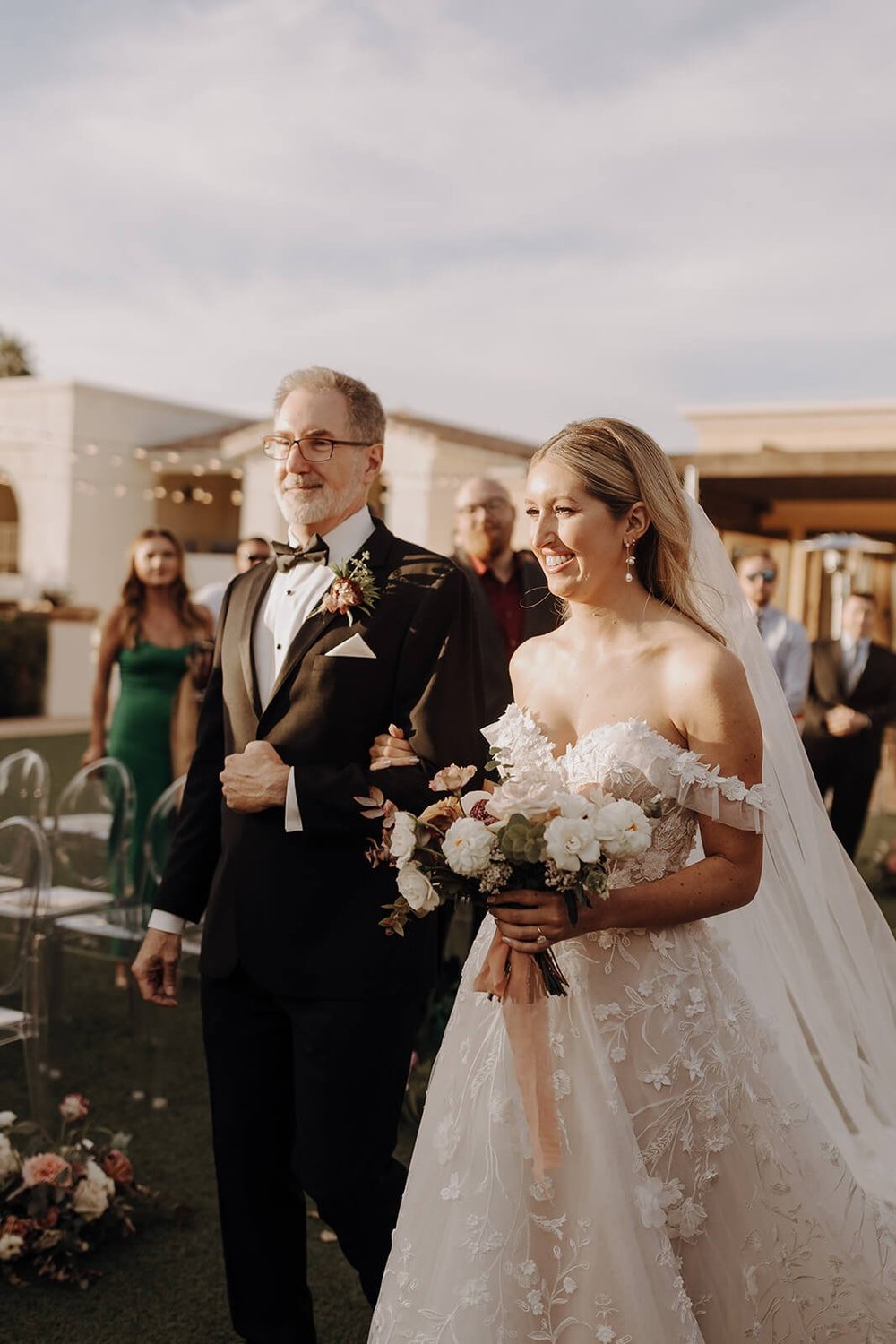 Father of the bride walks bride down the aisle at luxury outdoor wedding