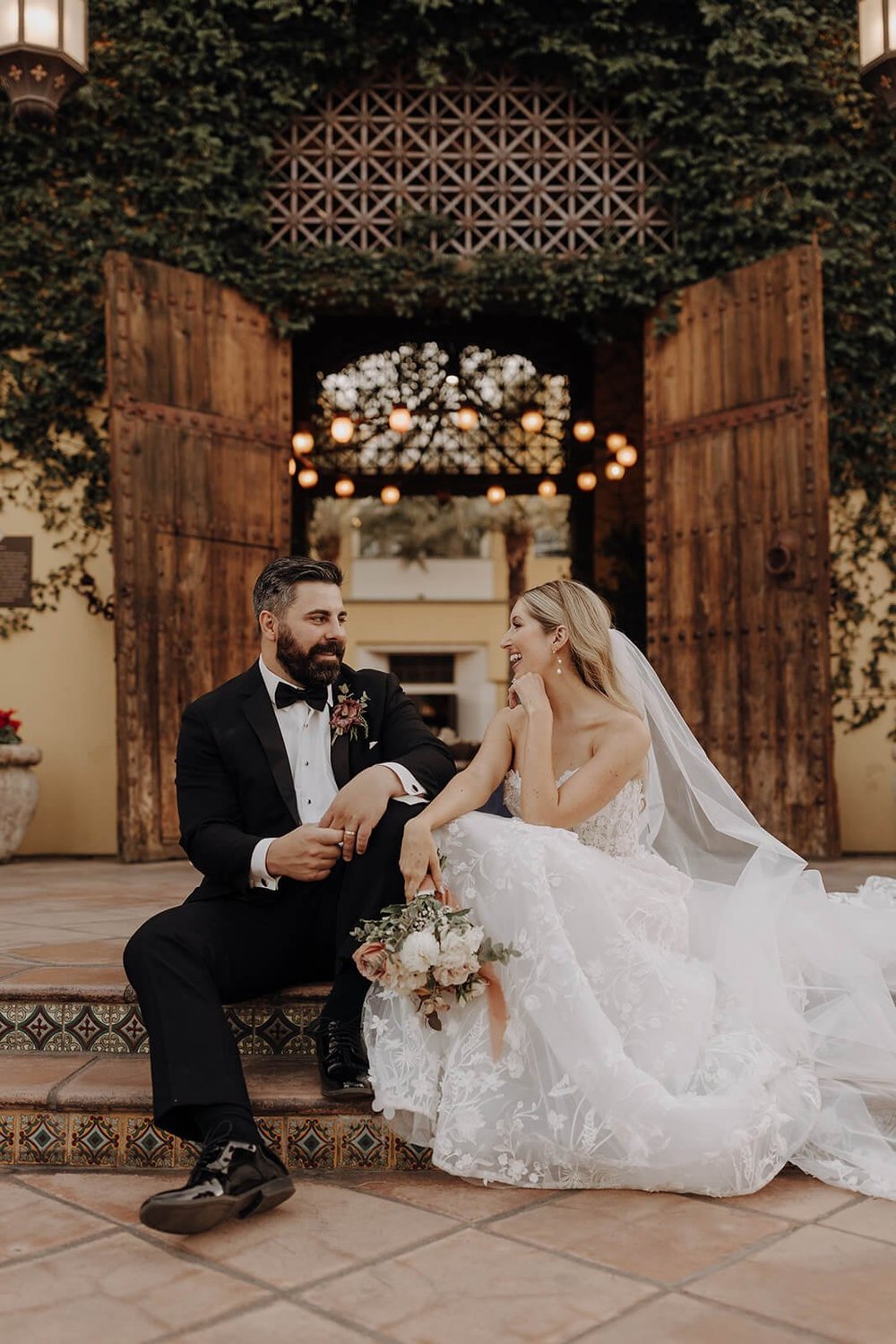 Bride and groom sitting outside in front of luxury Spanish style resort