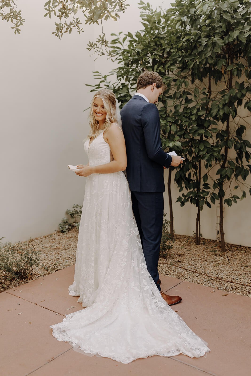 Bride and groom standing back to back reading vows