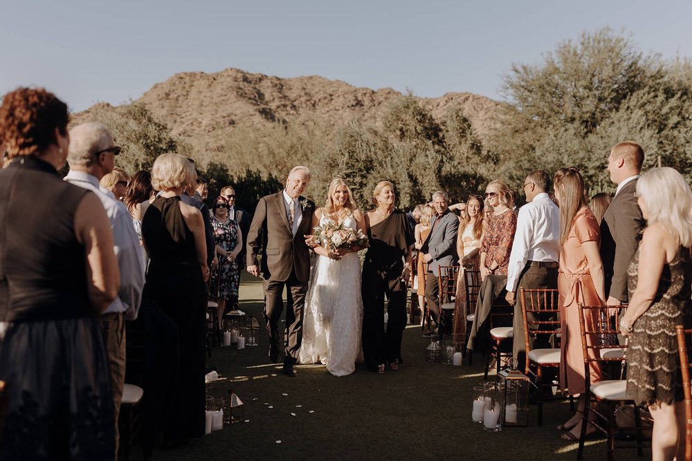 Desert wedding bride with parents walking down the aisle