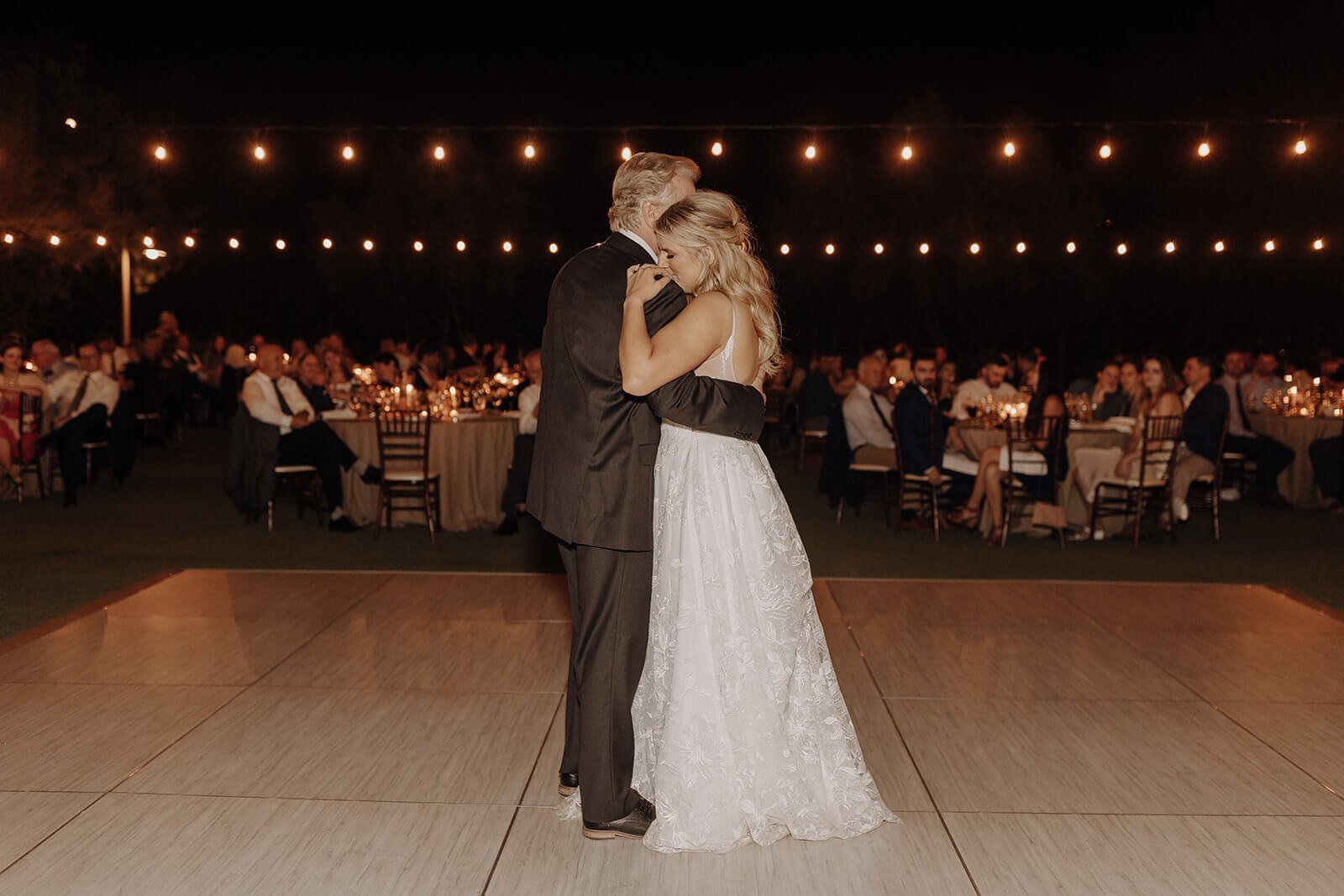 Bride dances with father at evening outdoor wedding reception