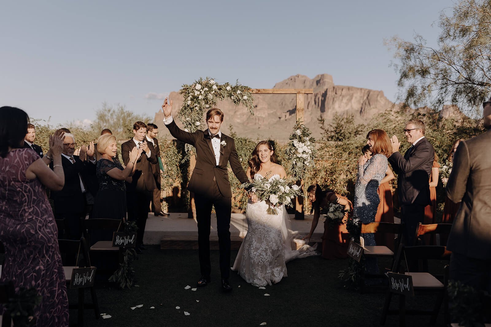 Bride and groom cheer as they exit the wedding aisle at Arizona desert wedding