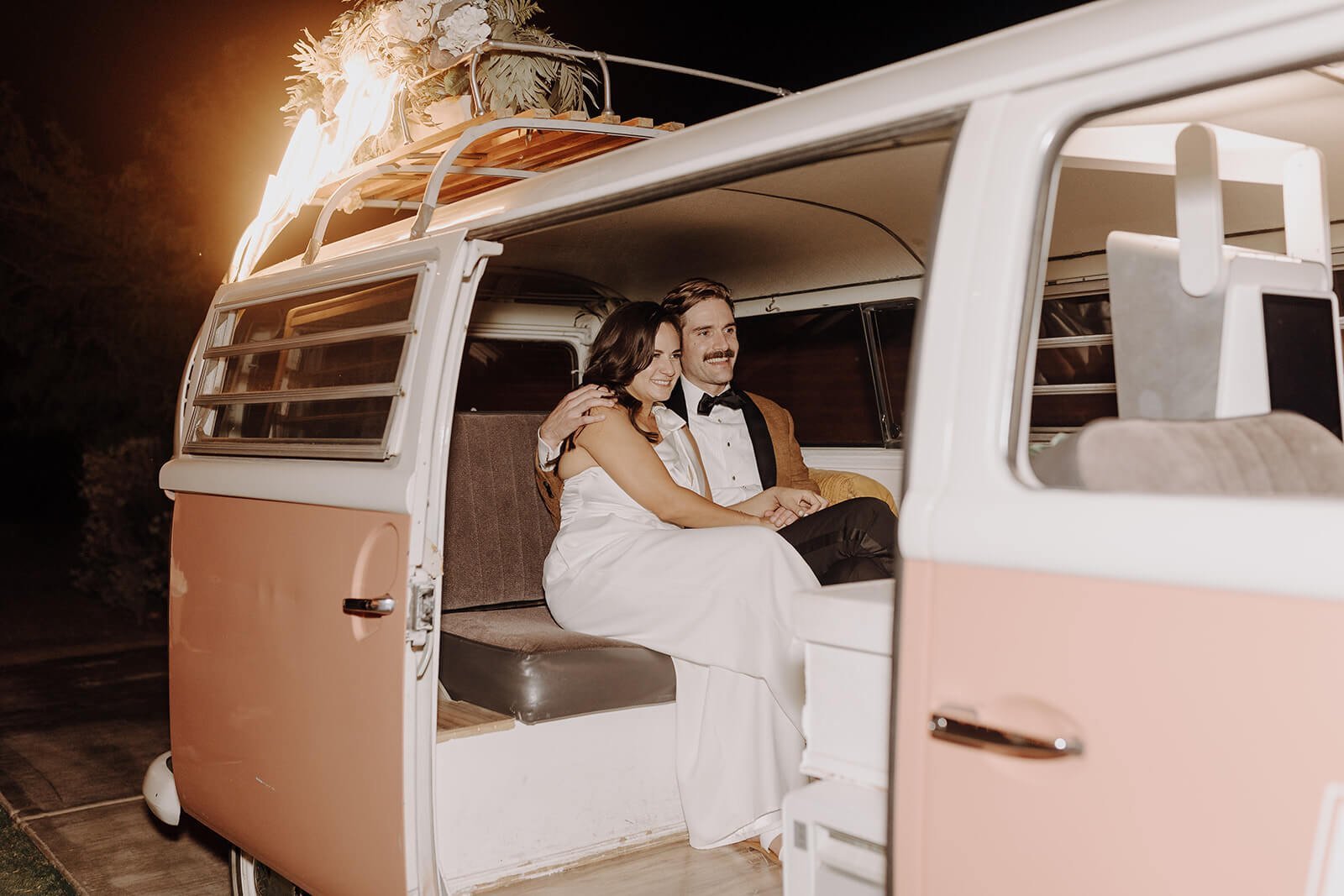 Bride and groom sitting in pink photo bus at The Paseo 