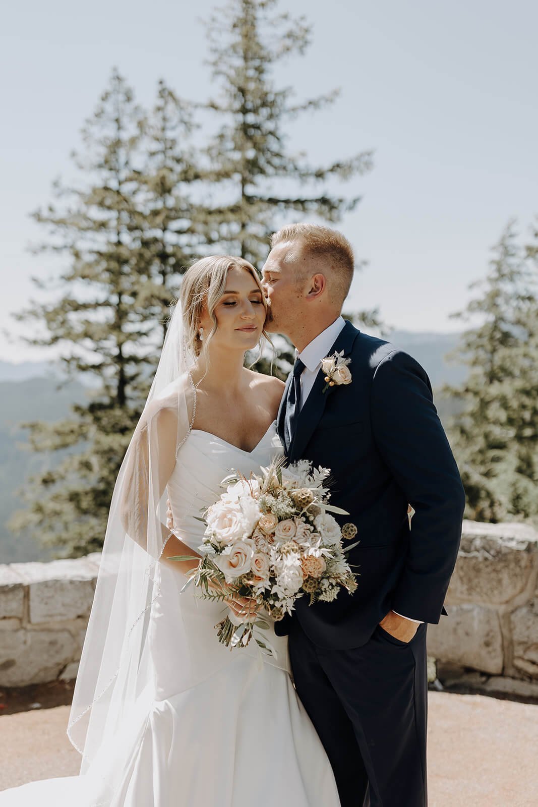 Groom kissing bride on the cheek during Mount Rainier wedding portraits