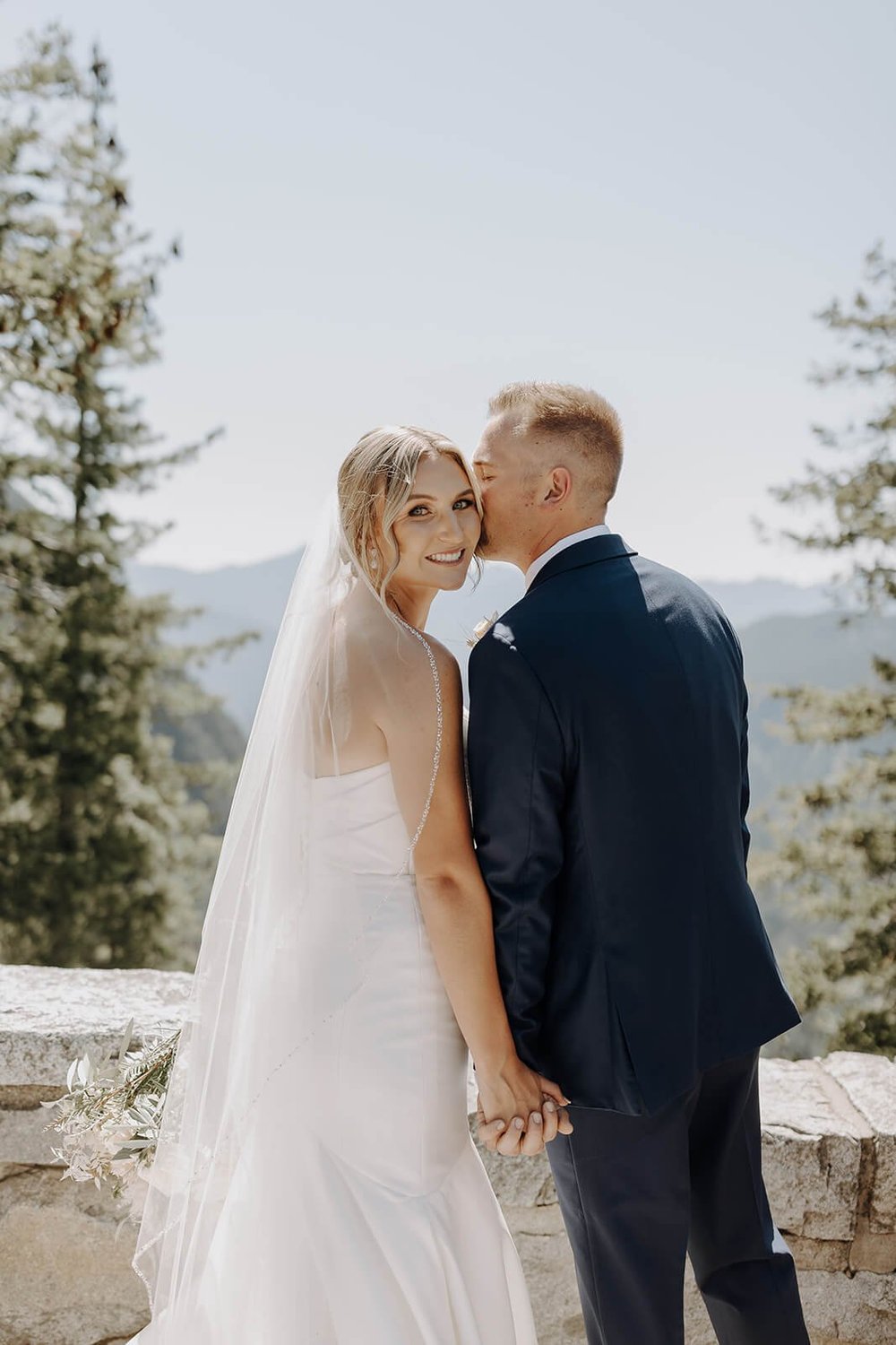 Groom kissing bride on the cheek during wedding portraits at Mount Rainier
