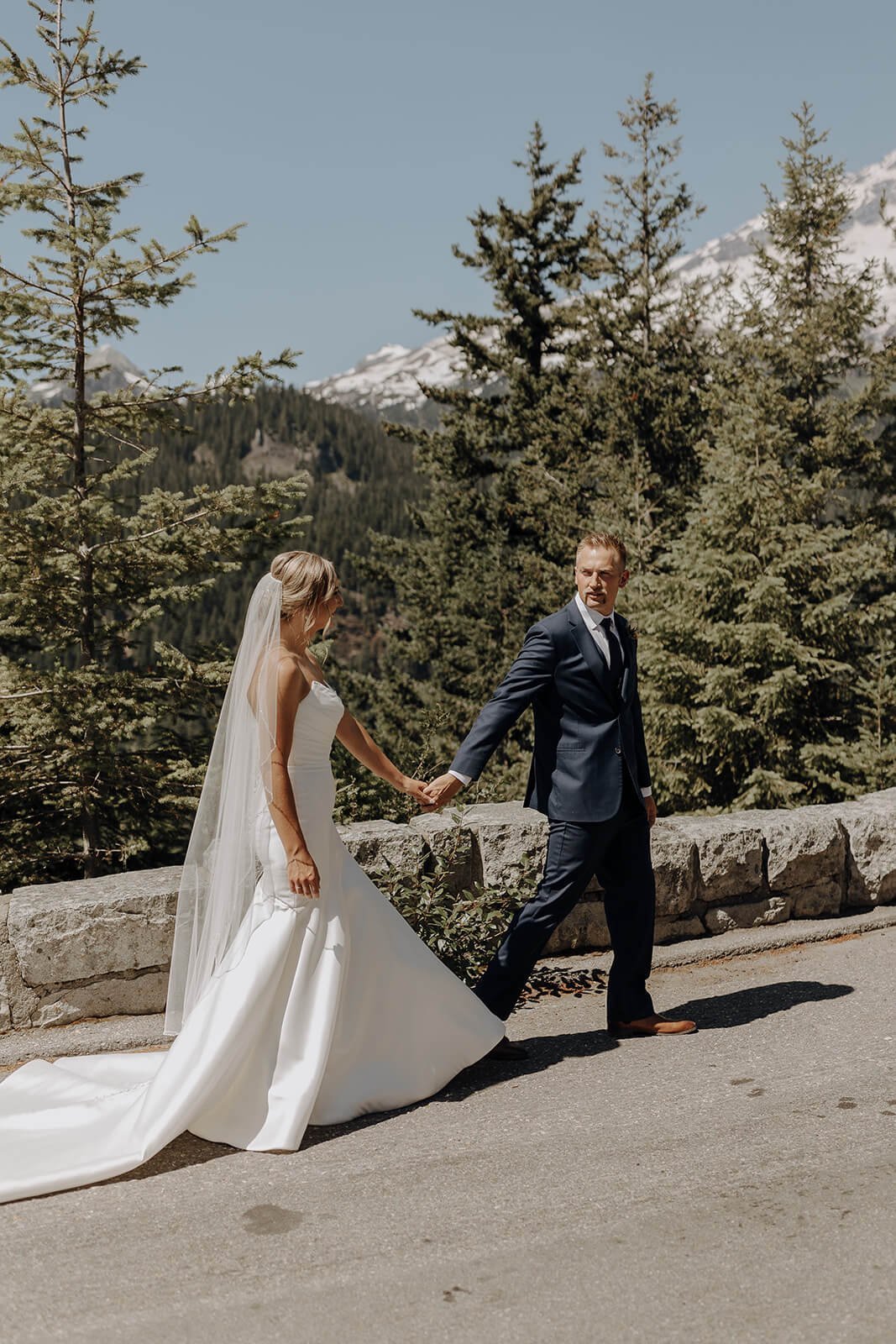 Bride and groom holding hands walking along trail at Mount Rainier