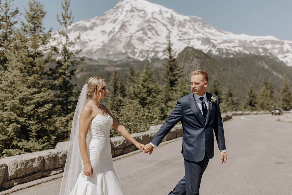 Bride and groom holding hands in front of Mount Rainier