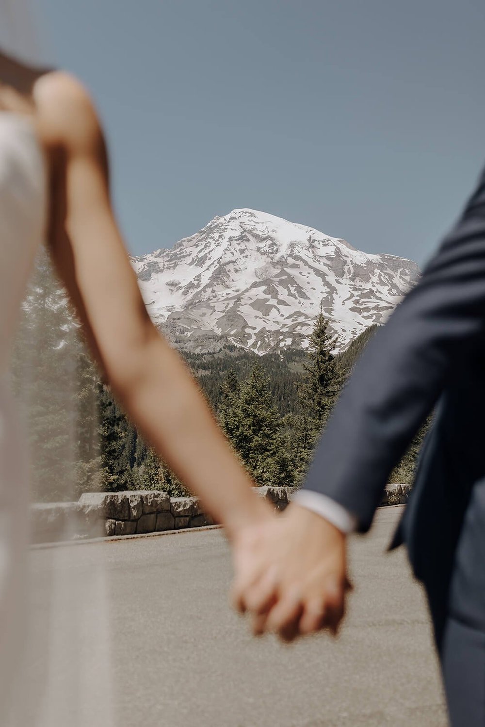 Bride and groom hold hands in front of Mount Rainier