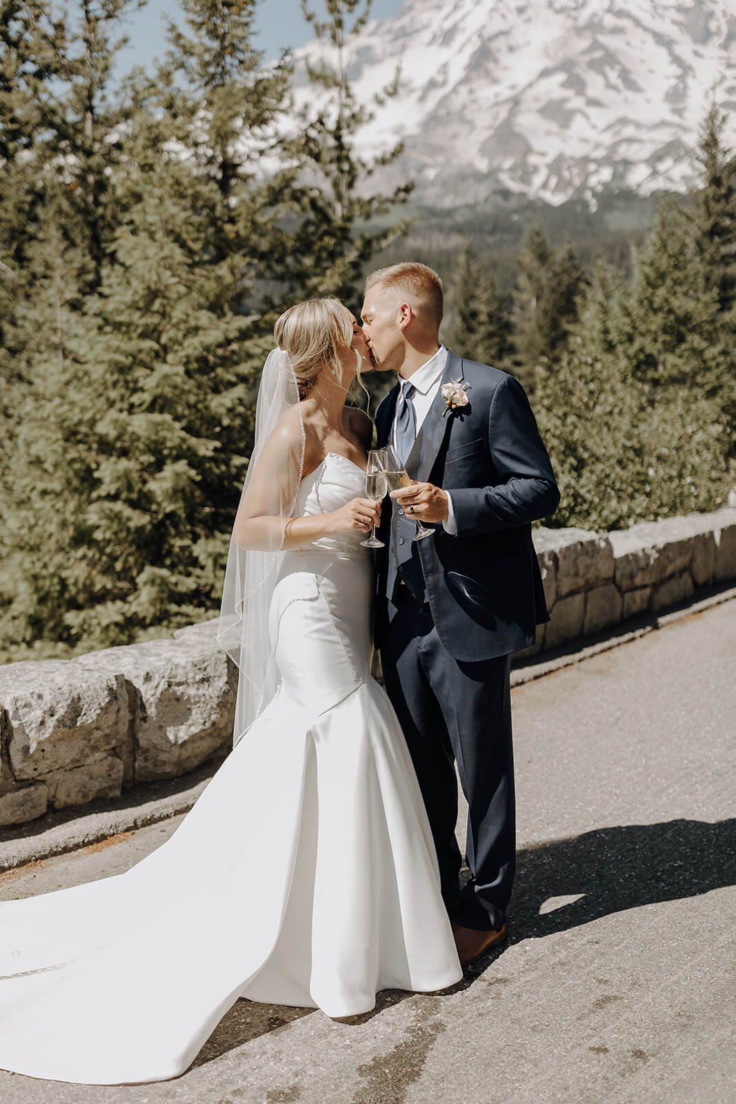 Bride and groom kiss while holding champagne glasses