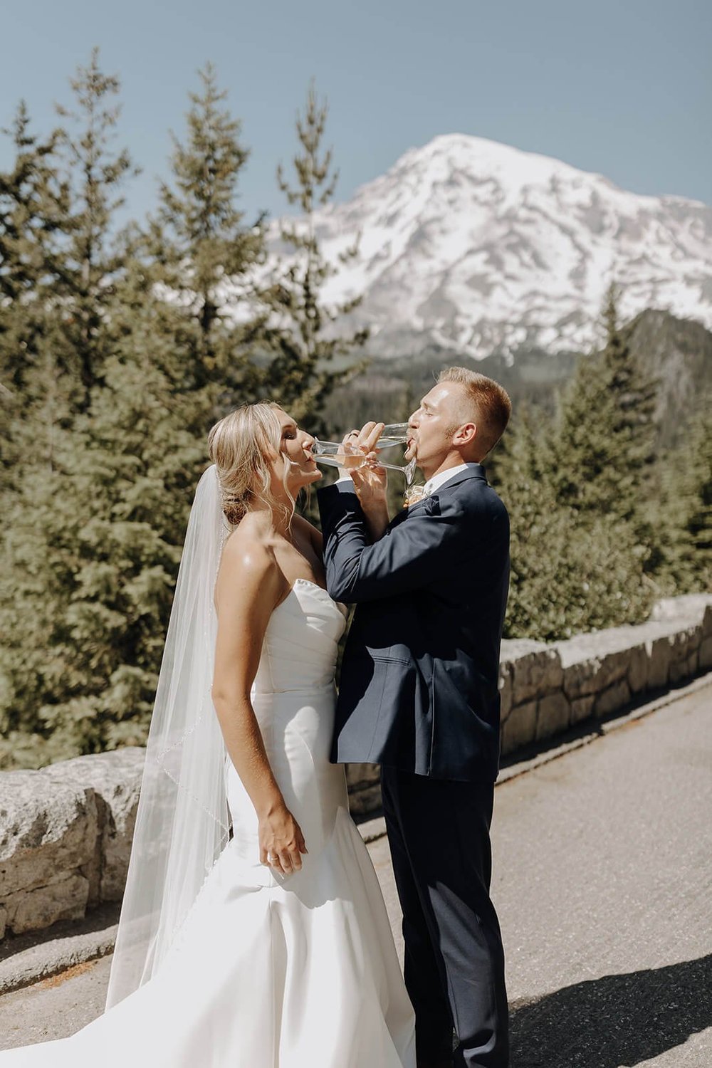 Bride and groom drink champagne together at Mount Rainier wedding