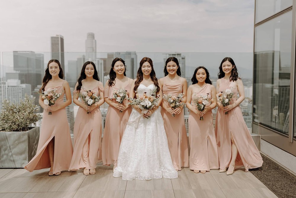 Bridesmaids in pink dresses standing on the top of a building overlooking LA