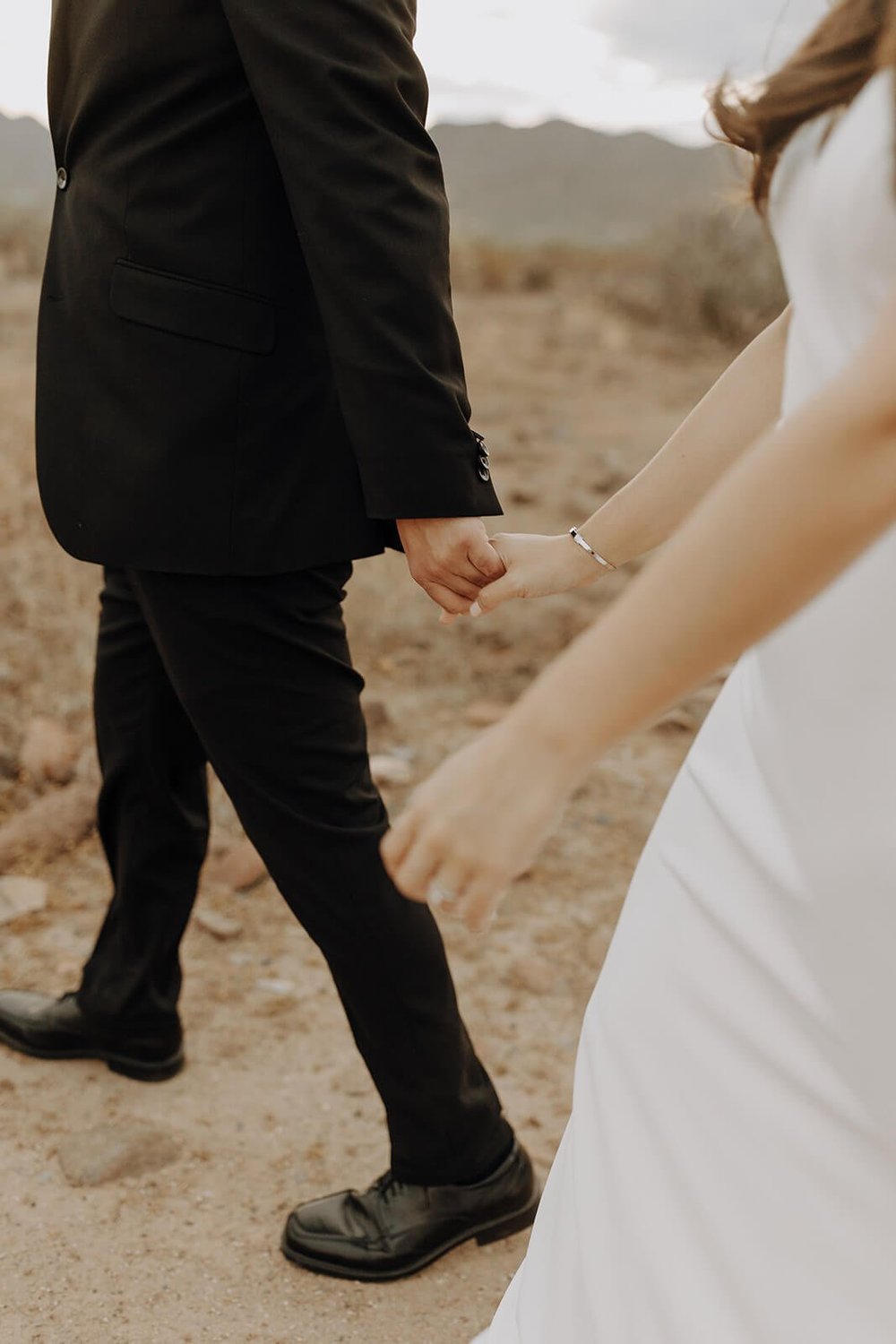 Bride and groom holding hands while walking through the Arizona desert