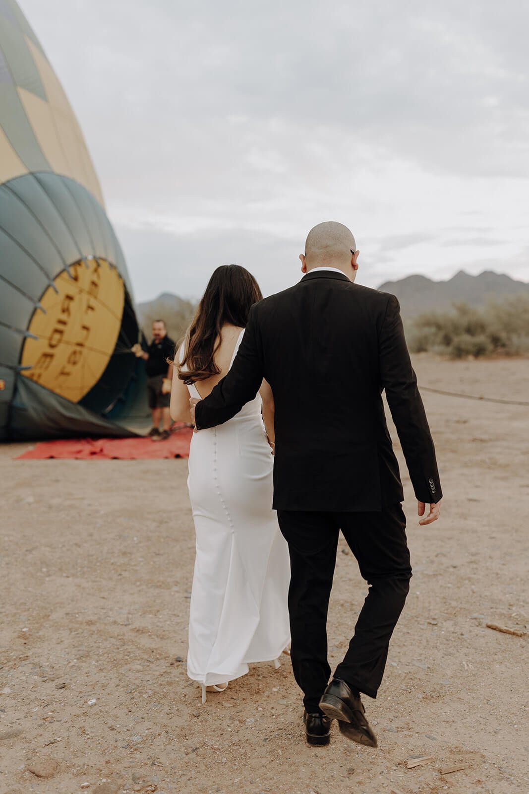 Bride and groom walking towards colorful hot air balloon