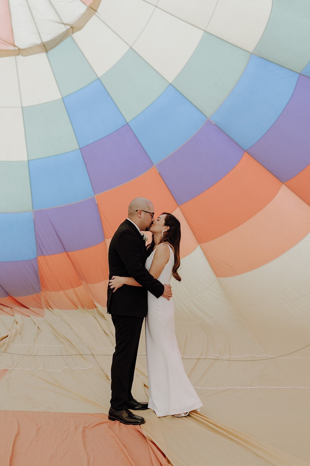Bride and groom kiss during hot air balloon elopement ceremony