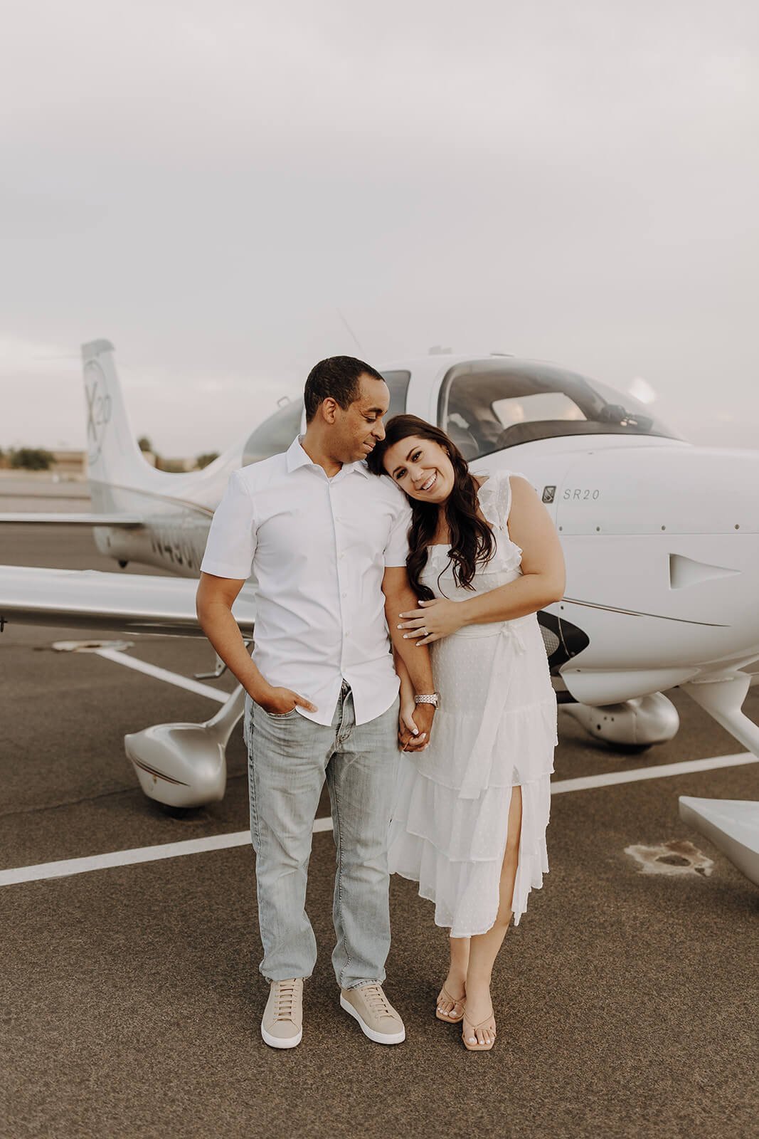 Couple hugs in front of airplane for unique engagement photos