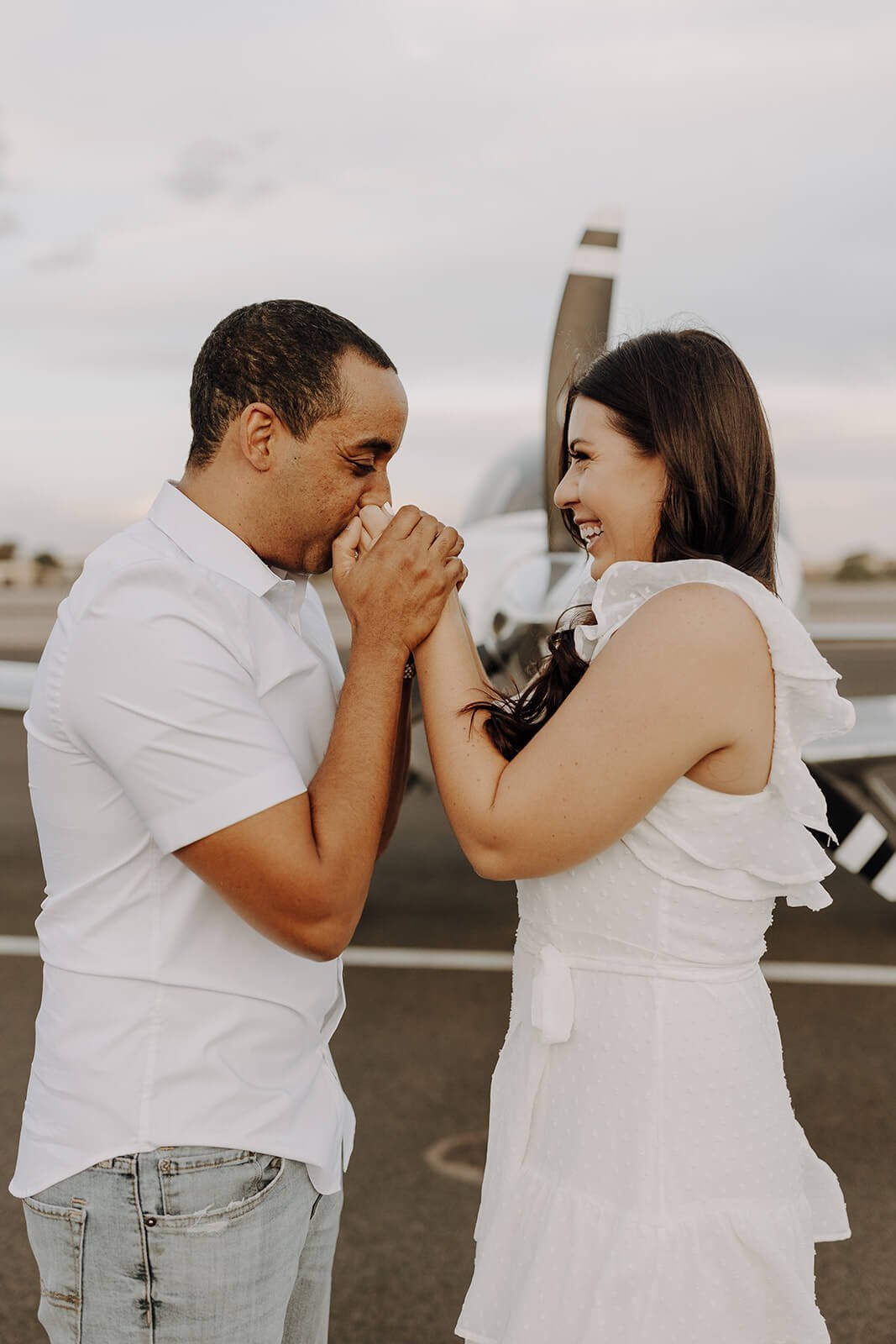 Man kisses woman's hands during unique engagement photos at Scottsdale airport