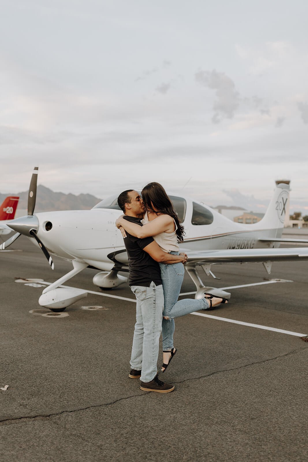 Man and woman kissing on the air strip during unique engagement photos