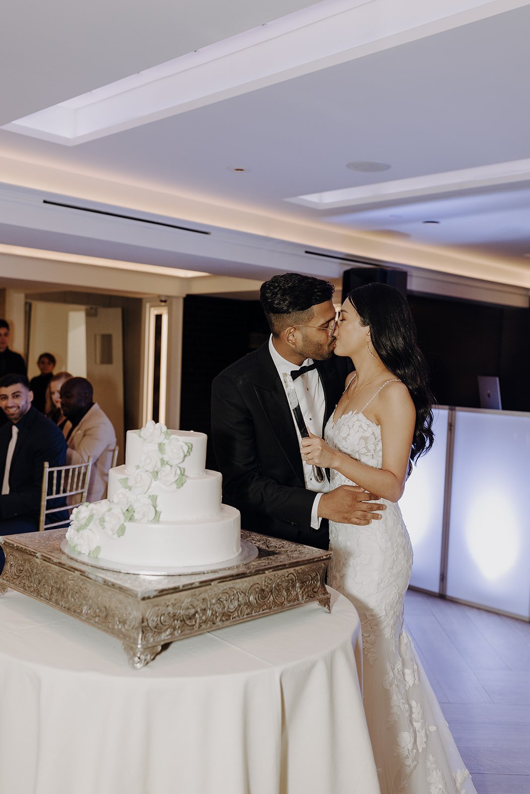 Bride and groom kiss before cutting cake at city wedding in NY