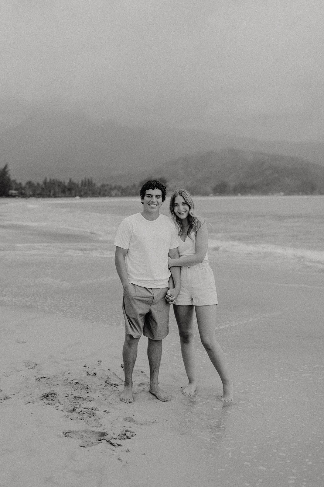 Couple holding hands and smiling on the beach in Kauai for their Hawaii engagement photos