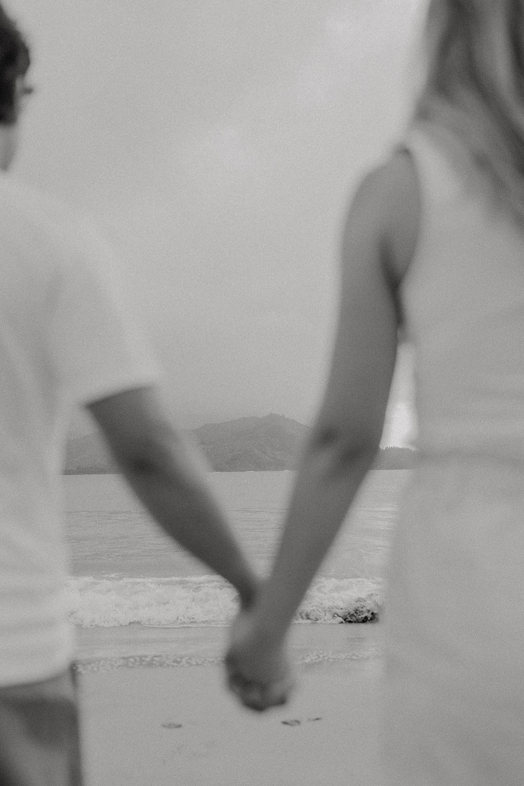 Couple holding hands and looking out into the ocean for their Kauai engagement photos