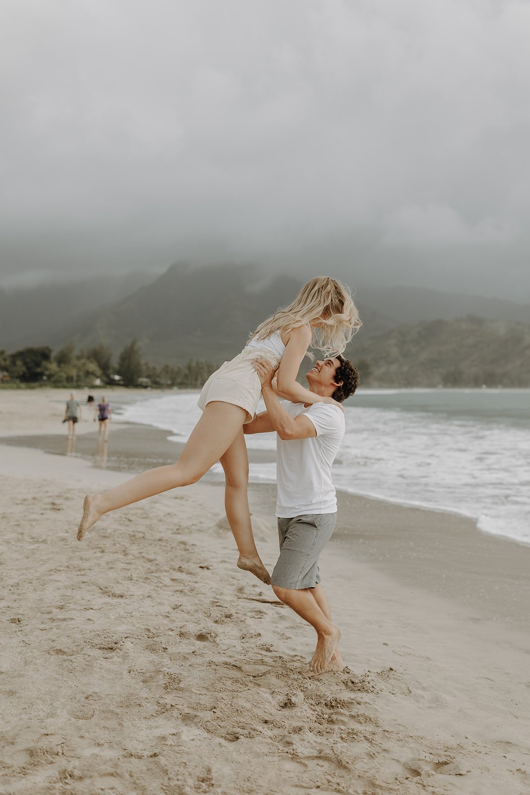 Man lifting woman into the air during Kauai engagement photo session