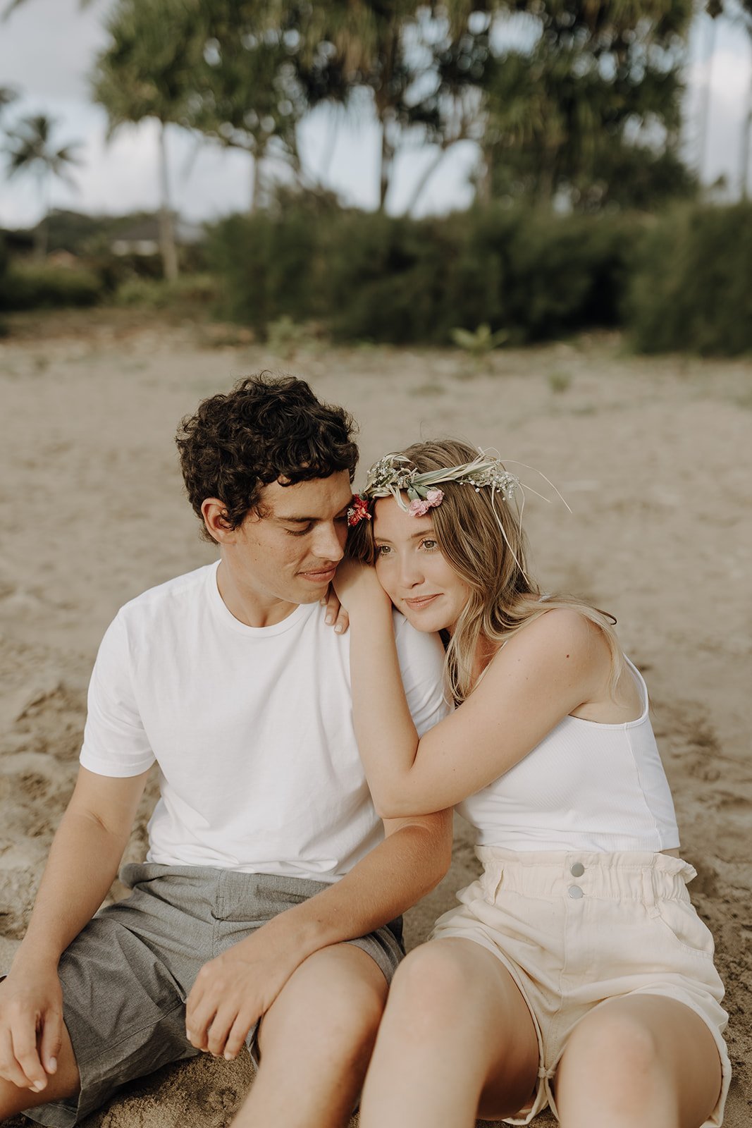 Couple sitting on the beach during Hawaii engagement photos
